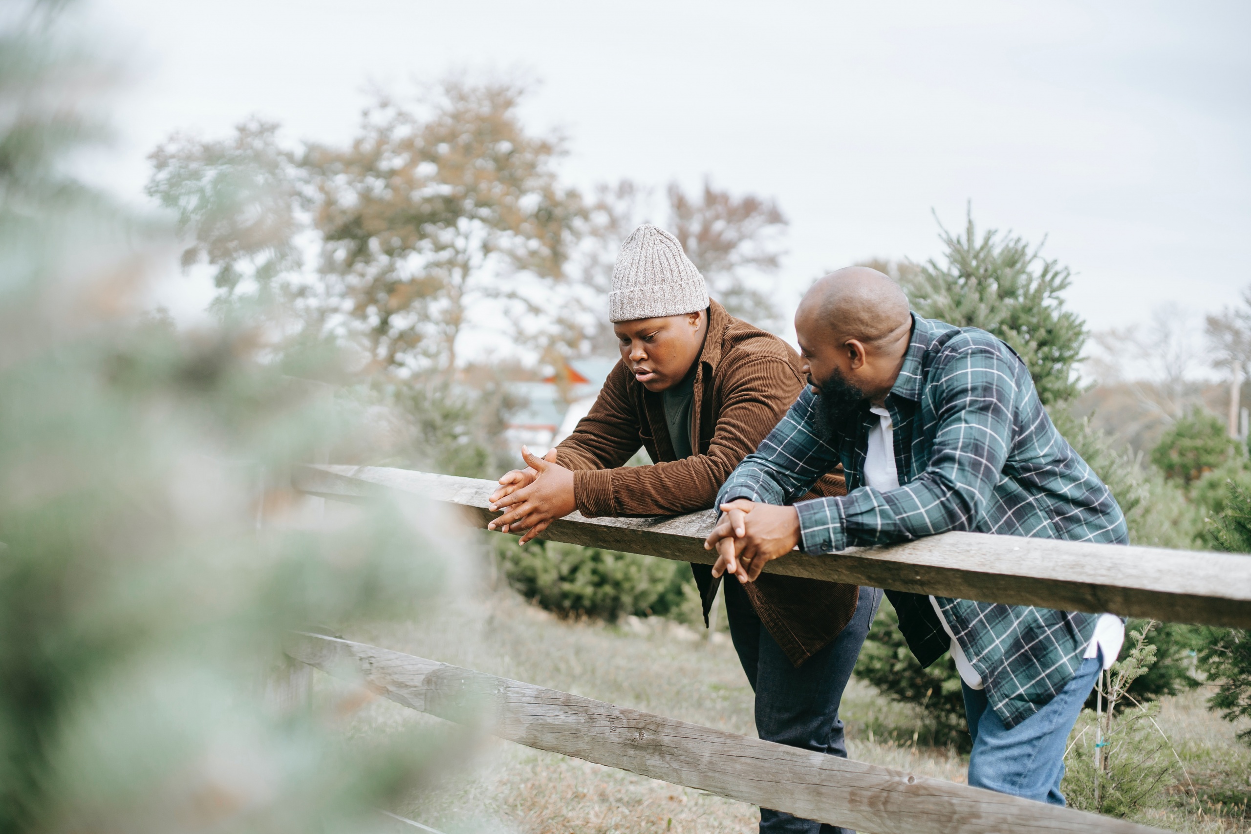 Father and son leaning against a fence talking